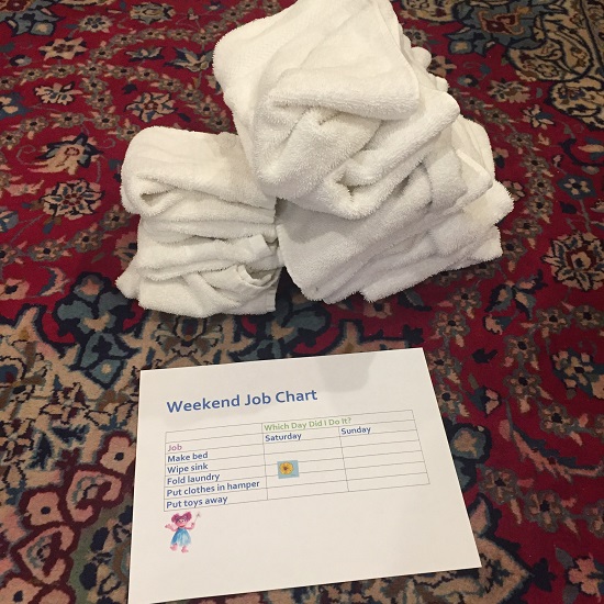 white hand towels and washcloths in messy stacks, with a list of weekend chores